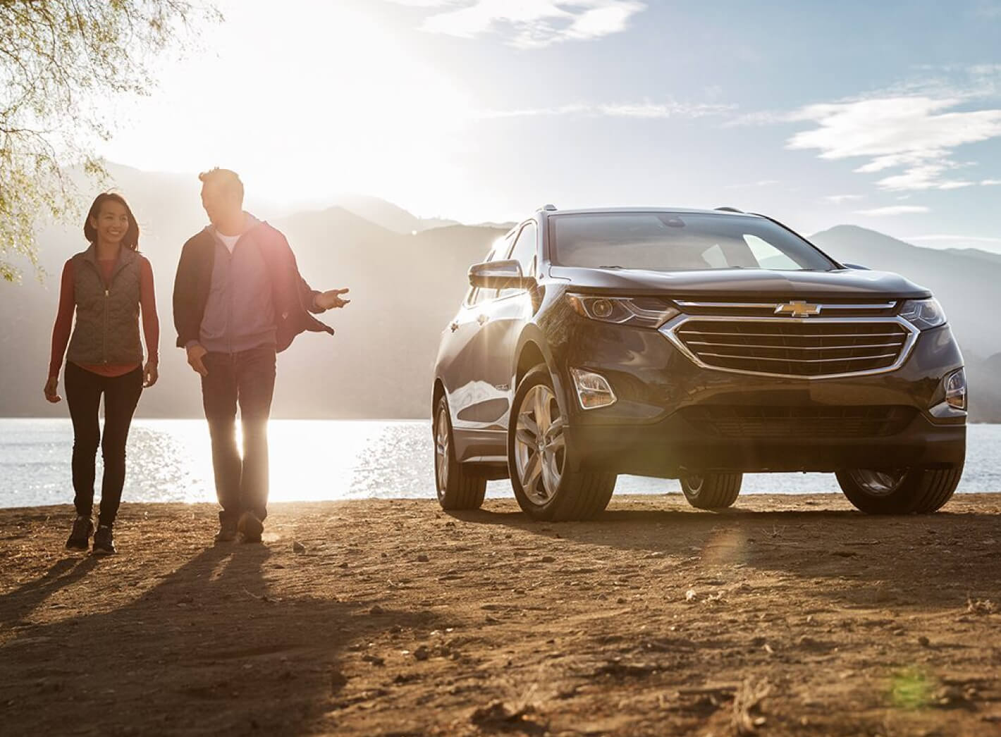 Three-quarter front view of a Nightfall Gray Chevrolet Equinox Premier parked by a lake.