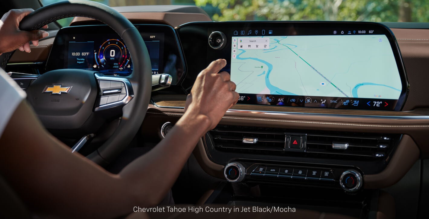 Close-up interior view of a Chevrolet Tahoe High Country showcasing a driver interacting with touchscreen display.